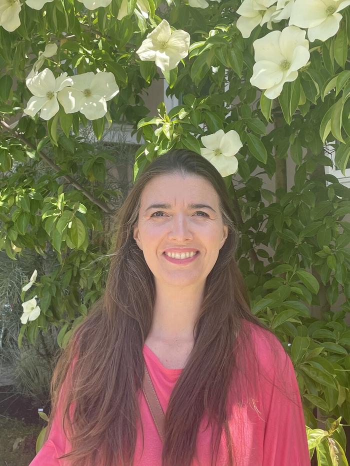 Ana Barrios standing in front of a white-blooming shrub