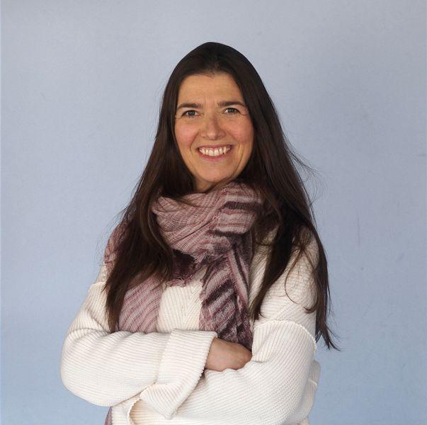 Ana Barrios smiling, arms crossed, wearing a scarf
